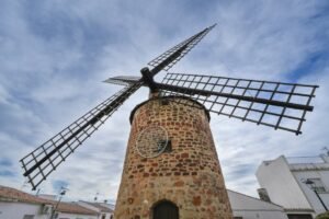 Charming historic windmill under a cloudy sky in Baños de la Encina, Spain.