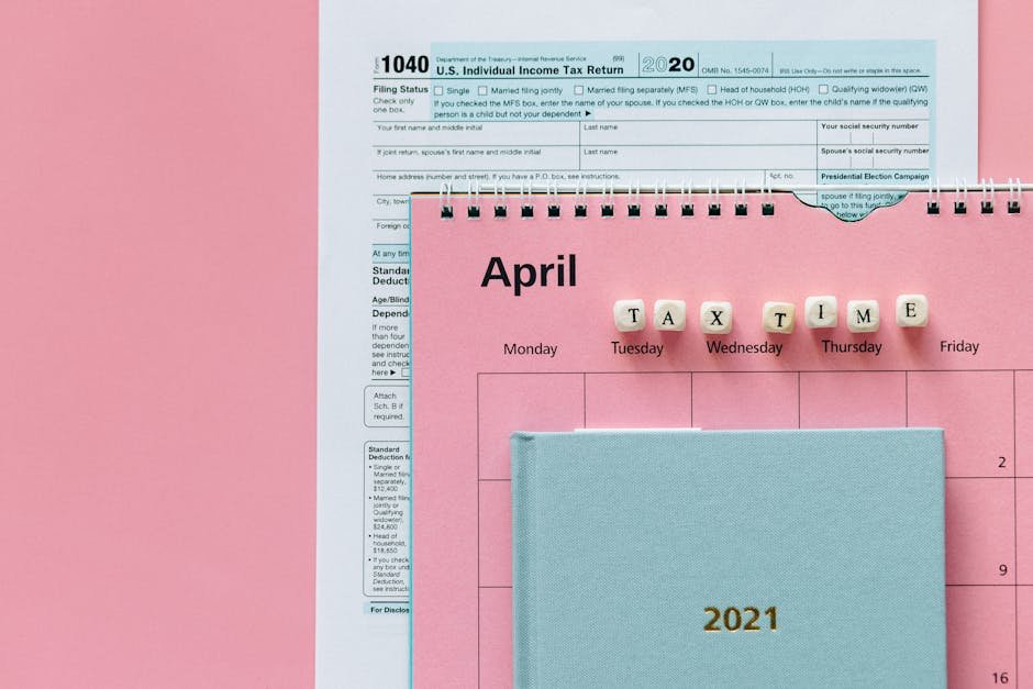 Flat lay image of tax forms, calendar, and 'tax time' reminder on a pink background.