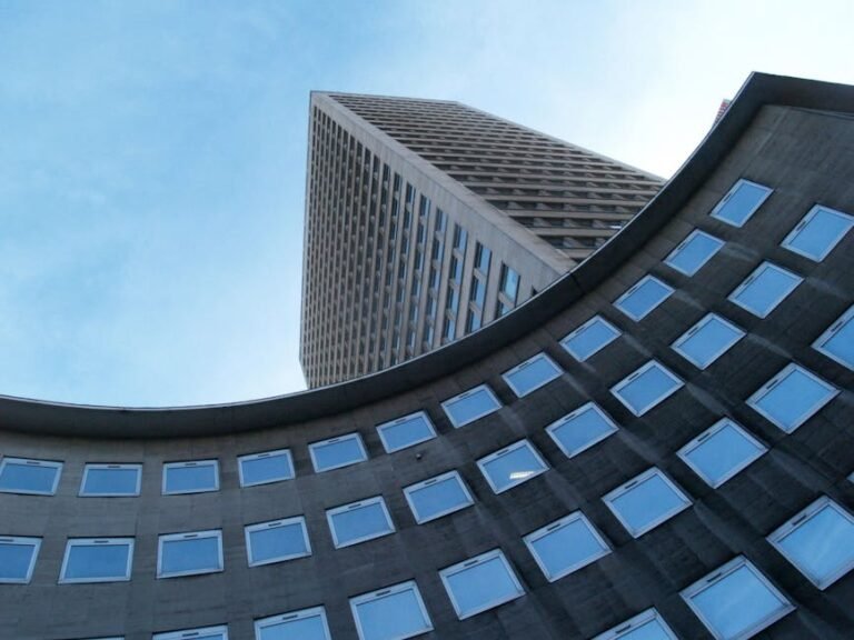 Low angle view of futuristic skyscraper with glass windows and geometric design.