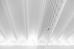 A modern minimalist shot of a volleyball and net indoors, emphasizing geometric patterns and soft lighting.
