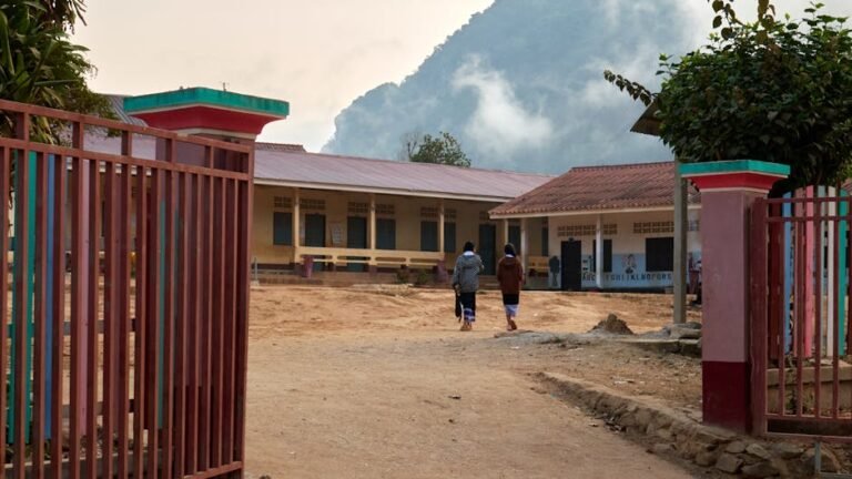 Women walking towards a rural school in Nong Khiaw, Laos, surrounded by mountains.