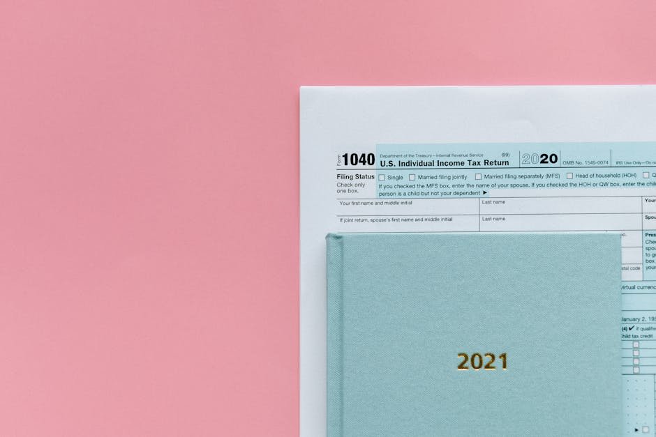 U.S. 1040 tax form with 2021 planner on a pastel pink background, symbolizing tax season.
