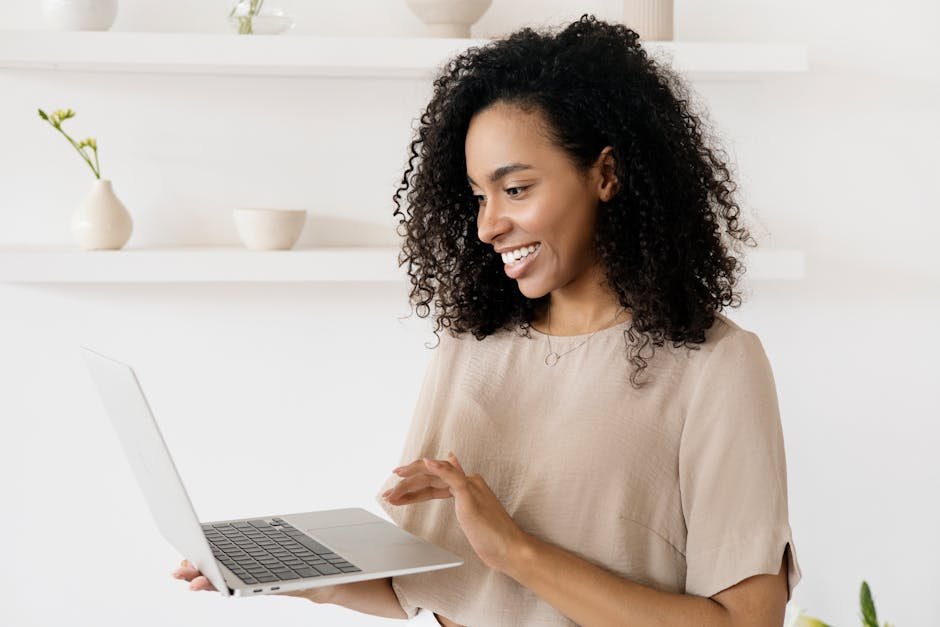 Smiling woman working on a laptop in a modern home office, highlighting freelance lifestyle.