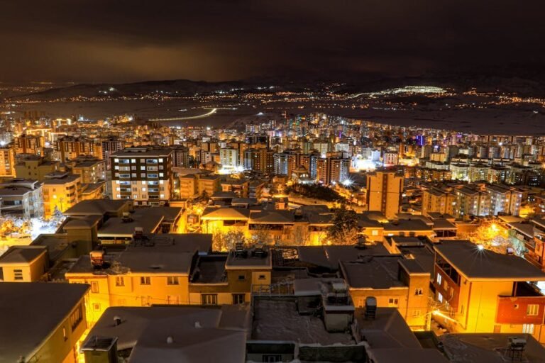 Aerial view of snow-covered Kahramanmaraş city illuminated at night, showcasing urban lights and winter charm.